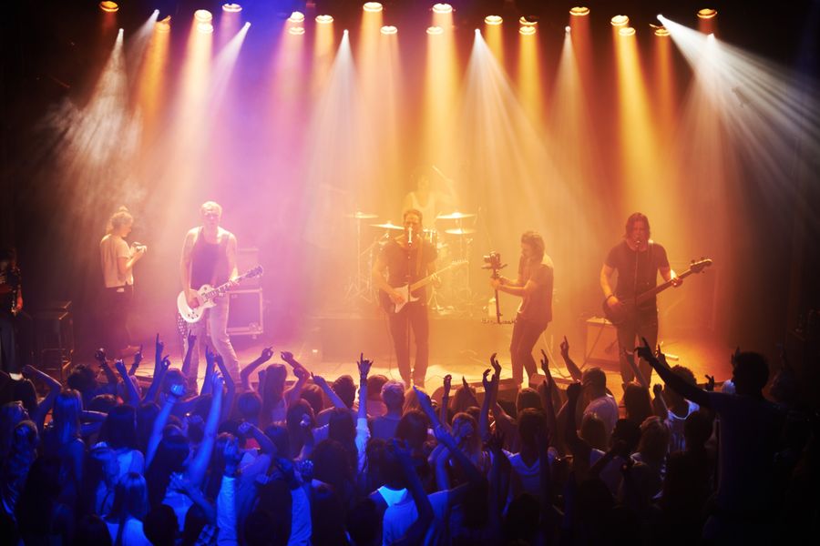 Scène de concerts avec lumières jaunes et bleues et la foule déchaînée dans la fosse