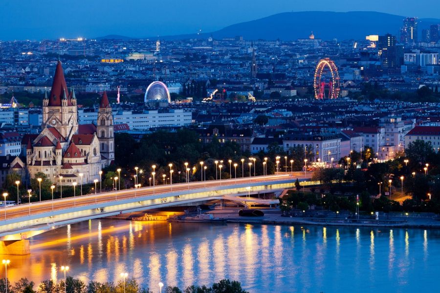 A photo of Vienna taken at night, using a slow shutter speed so the ferris wheel in the background is slightly blurred. 