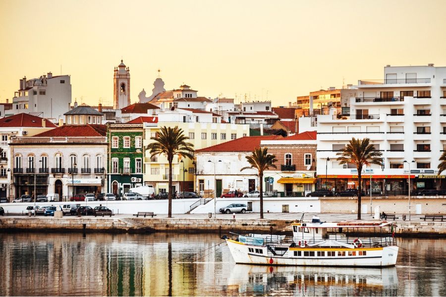 A photo of a port in the Algarve, taken at sunset, with a small boat in the foreground. 