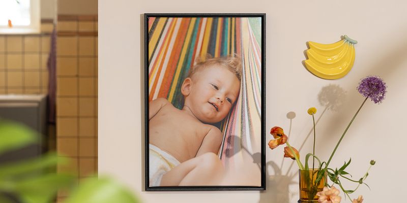 A piece of personalised Photobox wall art showing a baby next to flowers and fruit decor, inspiring bright and playful home decor for summer.
